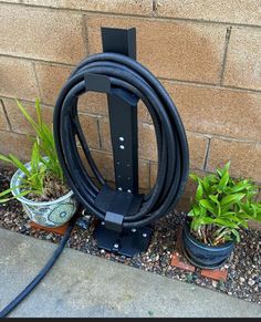 a garden hose is attached to the side of a brick wall next to potted plants