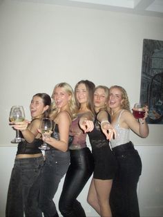 four women are posing with wine glasses in their hands