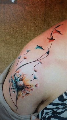 a woman's stomach with a dandelion tattoo design on it, and birds flying around