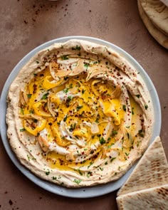 hummus and pita bread on a plate with some crackers next to it