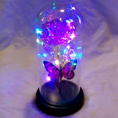 a purple butterfly sitting on top of a glass dome filled with light up decorations and lights