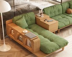 a green couch sitting next to a wooden table on top of a hard wood floor