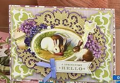 a close up of a greeting card with rabbits and flowers in the background on a table