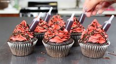 chocolate cupcakes with red frosting and sprinkles are being cut