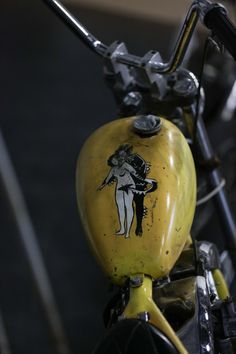 the handlebars on this yellow motorcycle are decorated with an image of a woman