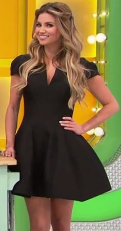 a woman standing in front of a table wearing a black dress and smiling at the camera