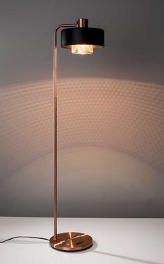 a floor lamp that is on top of a white table and has a black shade