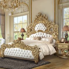 an ornate gold and white bedroom with chandelier, bed, dresser and mirror