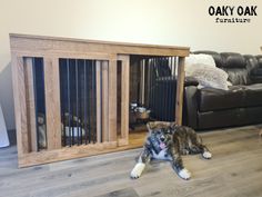 a dog is laying on the floor in front of a wooden crate with bars attached to it