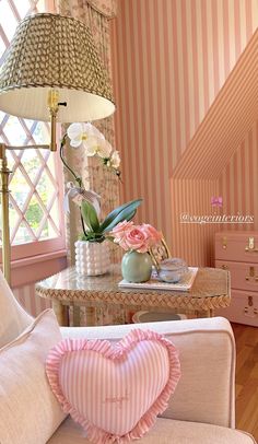 a living room with pink and white striped wallpaper, a love heart shaped pillow on the sofa