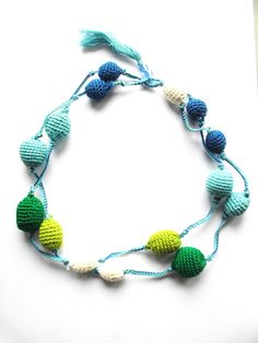 a crocheted necklace with beads and tassels on a white table top