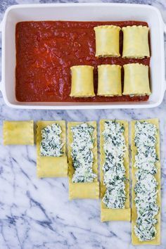 some ravioli and sauce in a white casserole dish on a marble counter