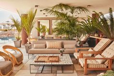 a living room filled with lots of furniture next to a swimming pool and palm trees