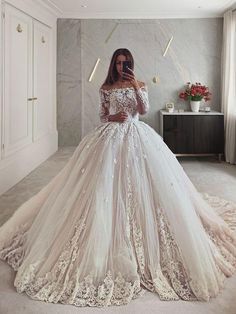 a woman in a wedding dress taking a selfie with her cell phone while standing in front of a mirror