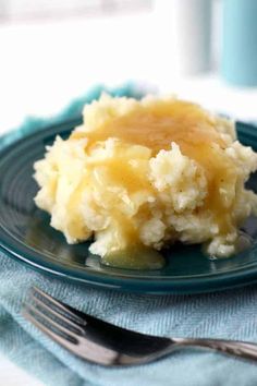 a blue plate topped with mashed potatoes covered in gravy