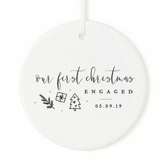 a white ornament with the words our first christmas is engaged and a pine tree