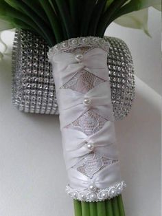 the bouquet is made up of white flowers and ribbons with pearls on them, along with green stems