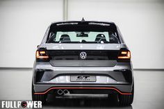 the rear end of a silver volkswagen car in a garage with white walls and black flooring