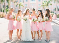 a group of women standing next to each other in pink dresses and holding bouquets