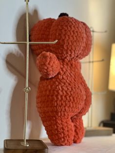 a crocheted teddy bear standing next to a lamp