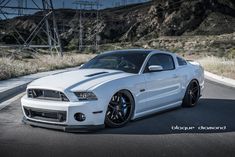 the white mustang is parked on the side of the road