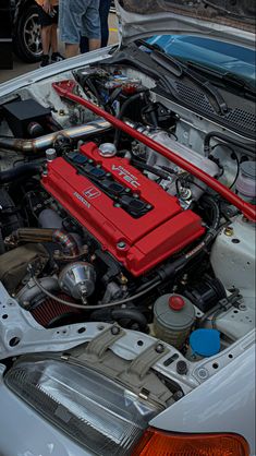 the engine compartment of a car with its hood open and it's red battery cover