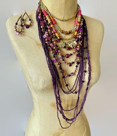 This is an instant, exotic bohemian influenced collection! Let your bohemian soul sing with this layered set of 3 necklaces plus a pair of earrings.  Wear them together or on their own to create different looks. The necklaces are a combination of metals, patterns materials and finishes for an amazing assortment!  Fabulous shades of purple. pink gold, and silver metal, etc.   (1) The shortest necklace is marked Loft on the hang tag.  Several strands feature a beautiful mixture of beads in purple, hot pink, gold etc, They are made from glass, wood, metal, etc.  Beautiful necklace with lots of sparkle!  The shortest strand is 16".  Very good condition.  Metal wear on just the first jump ring where the clasp closes on it (2) The middle necklace is created from 4 strands with shades of purple a Bohemian Soul, Deep Pink, Purple Glass, Layered Necklace, Short Necklace, Beautiful Necklace, Wood Metal, Shades Of Purple, Multi Strand