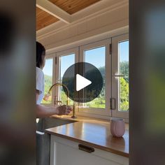 a woman standing in front of a kitchen counter with a sink and faucet