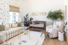 a living room filled with furniture next to a baby's crib and potted plant