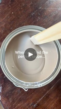 a person using a brush to paint the inside of a jar on a wooden table