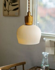 a white lamp hanging from a ceiling in a room next to a table and chairs