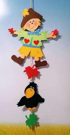 a child's hanging decoration featuring a scarecrow and a bird