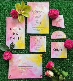 pink and yellow wedding stationery with flowers on green artificial grass for an outdoor ceremony