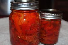 two jars filled with pickles sitting on top of a table