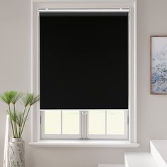 a black roller shade in a bathroom window with white countertop and sink below it