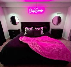 a bed that has a pink blanket on it in a room with two round mirrors