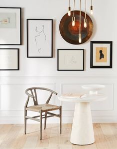 a white table and chair in a room with pictures on the wall