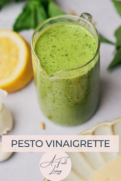 pesto vinaigrete in a glass with lemons and basil on the side