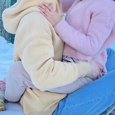 two people sitting in the snow one is kissing the other's face while the other holds her