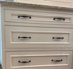 a white dresser with black handles and knobs