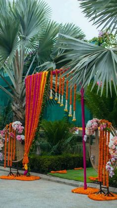 an outdoor wedding setup with orange and pink flowers on the ground, palm trees in the background