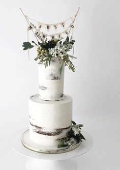 a white wedding cake with greenery and bunting