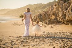 the mother and daughter are walking on the beach with their bouquets in each hand