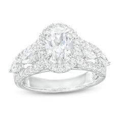 a white gold ring with an oval cut diamond surrounded by round and pear shaped diamonds