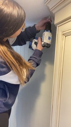 a woman is using a paint roller to fix a door handle on an old cabinet