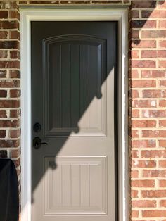 the shadow of a person standing in front of a gray door on a brick building