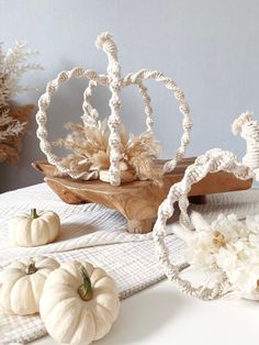 some white pumpkins are sitting on a table with other things around them and one is in the middle