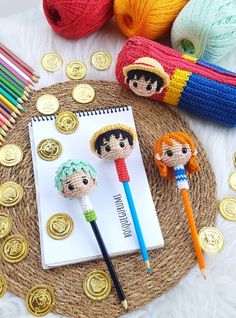 two crocheted dolls sitting on top of a table next to some knitting supplies