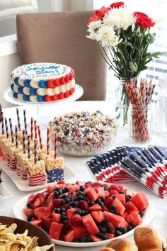 patriotic desserts and snacks on a table with flowers in vases at the end