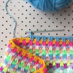 a crochet bag with a ball of yarn next to it and a knitting needle